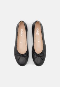 Ballet flats in pelle nera con punta tonda, bordi scallop e un fiocco decorativo sulla parte superiore. Soletta beige chiaro con marchio.