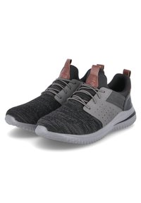 Zapatillas deportivas en negro y gris con parte superior de tejido texturizado, acentos sintéticos, pestañas traseras de cuero marrón y suela de goma blanca flexible.