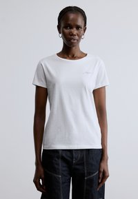 Fehér pamut rövid ujjú póló kerek nyakkivágással. A mellrészen kis lila hímzett szöveg található. Simított textúrájú.