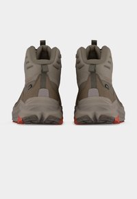 Ζευγάρι καφέ και γκρι ορειβατικών μπότες με επενδυμένους γιακάδες και κόκκινες λεπτομέρειες, εμφανιζόμενες από πίσω σε λευκό φόντο.