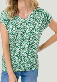 Top corto de mangas cortas con un patrón floral verde y escote en V, hecho de una tela ligera, que presenta acentos en blanco y azul y un corte relajado.