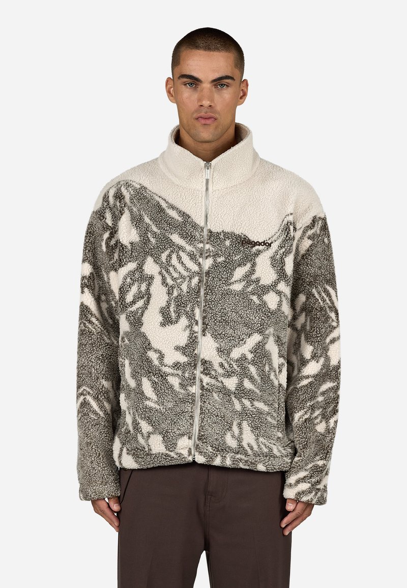 Polarowa kurtka z zamkiem błyskawicznym, w szaro-białym, teksturowanym wzorze. Posiada wysoki kołnierz i centralny zamek. Miękki, ciepły materiał.