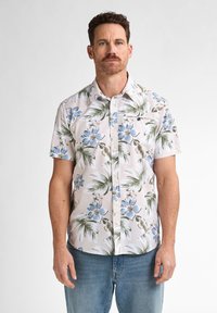 Camisa de botones de manga corta en tela ligera, con un patrón floral de flores azules y hojas verdes sobre un fondo pálido.