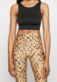 Donna che indossa un top nero senza maniche e leggings a vita alta con stampa leopardata, mostrata dalla nuca a metà coscia.