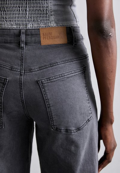 Gray denim jeans with a textured waistband, featuring two back pockets and a leather label reading "BAUM UND PERGARTEN."