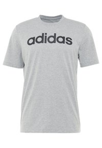 Šedé tričko s krátkým rukávem vyrobené z bavlny, s kulatým výstřihem a výrazným černým logem "adidas" potisknutým přes prsa.
