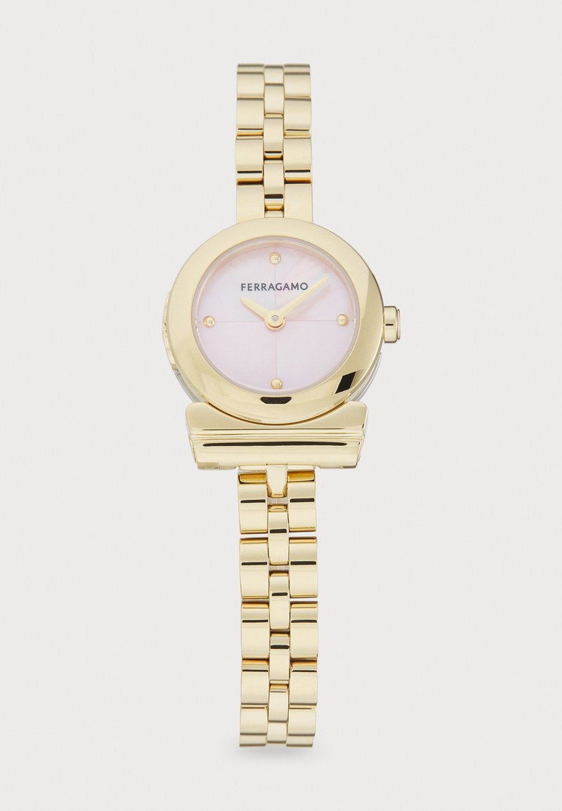 Reloj de tono dorado con esfera redonda, dial rosa y marcadores de hora minimalistas. Presenta una pulsera metálica enlazada y un estilo clásico.