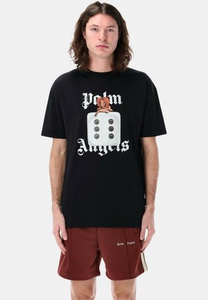 T-shirt nera con una grafica di un personaggio dei cartoni animati e un dado, con testo bianco che recita "Palm Angels". Maniche corte, vestibilità rilassata.