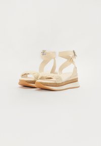 Beige kilehæle sandaler med flettet tårem, ankelremme og sølvspænde. Struktureret platform med jute-lignende udseende og gummisål.