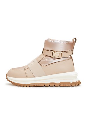Stivale alla caviglia beige con parte superiore imbottita, fascia elastica e dettaglio con fibbia. Presenta una suola in gomma texturizzata per grip e ammortizzazione.
