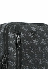 Borsa in tessuto nero con texture, caratterizzata da un motivo logo grigio, hardware argentato e un accento a forma di triangolo del logo. Sono visibili due scomparti con zip.