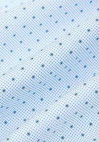 Biała tkanina z jasnoniebieskimi i ciemnoniebieskimi geometrycznymi wzorami, z kropkami i krzyżykami ułożonymi w teksturowy wzór.