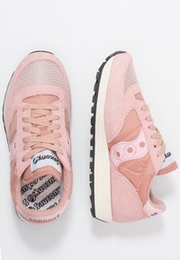 Paire de baskets Saucony roses avec des détails en maille et en suède, une chaussure vue de dessus et l'autre de côté sur un fond blanc.