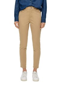 Beżowe dopasowane spodnie o gładkiej teksturze, w pełnej długości, z kieszeniami, w połączeniu z białymi sneakersami i niebieską koszulą dżinsową.