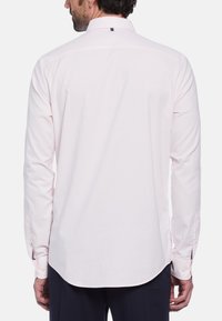 Lichtroze blouse met lange mouwen en een afgeronde zoom, met knoopmanchetten en een kraag. Bevat een klein merkteken in de nek aan de achterkant.