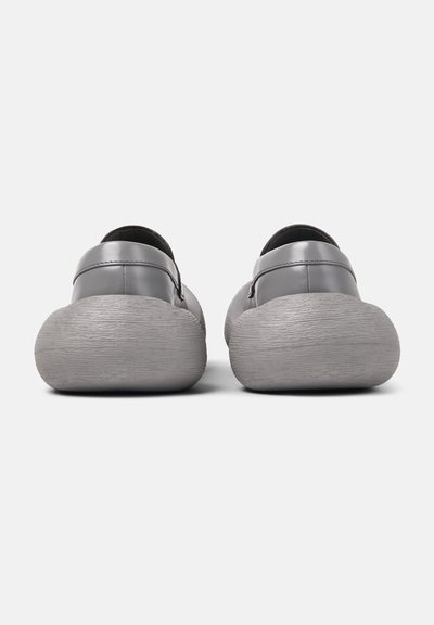 Gray slip-on shoes with a smooth leather upper and textured rubber soles, featuring a rounded shape and minimalistic design.