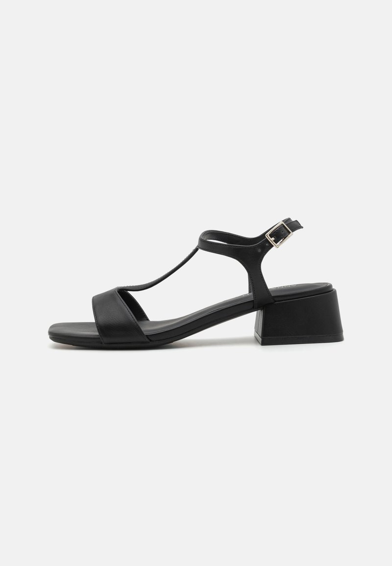 Sandalia de cuero negro con diseño de tira en T, correa de tobillo ajustable con hebilla y tacón cuadrado. Textura suave y mate en toda la superficie.