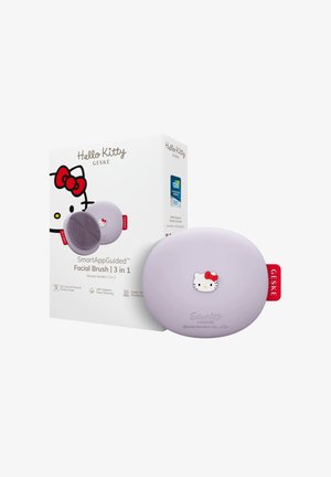 Brosse faciale ovale Hello Kitty lavande avec étiquette rouge à côté d'une boîte assortie présentant le visage de Hello Kitty et les détails du produit.