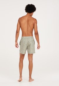 Groene zwembroek met een patroontje, voorzien van een elastische tailleband en zijzakken, met een geometrisch ontwerp, gezien vanaf de achterkant.