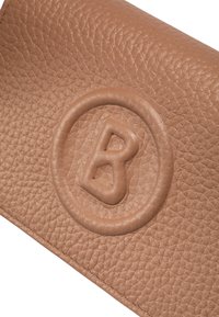 Portafoglio in pelle color cuoio con superficie texture e logo rotondo in rilievo con la lettera "B" al centro, bordi cuciti e design compatto.