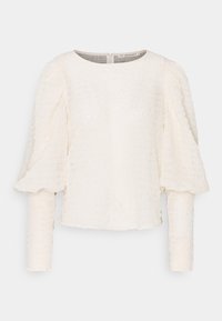 Vit texturerad långärmad blus med rund halsringning och puffärmar, med en synlig dragkedjestängning bak.