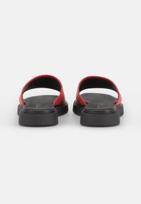Røde sandaler med åpen tå og en strømlinjeformet design, som har en glatt rød overdel og en kraftig svart såle for ekstra støtte og stabilitet.
