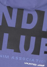 Lila hoodie med stor svart text "INDI" och marinblå "BLUE" med vit text "UNLIMITED APPAREL" nedanför, tillverkad av en bomullsblandning.