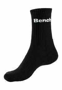 Calza nera a costine con suola imbottita, caratterizzata dal logo bianco "Bench" sul davanti. Il materiale sembra morbido ed elastico.