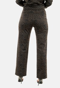 Pantalones de estampado de leopardo con una textura suave, diseño recto y acentos en negro, combinados con zapatos de tacón alto.