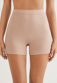 Ribbelachtige, hooggetailleerde shorts in een lichte tan kleur. Zachte textuur met een elastische tailleband, een aansluitende snit en een rechte zoom.