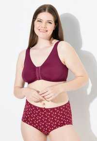 Soutien-gorge bordeaux avec un centre froncé et des bretelles larges, associé à des culottes taille haute assorties présentant un motif floral dans des teintes plus claires.