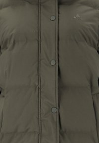 Olivenfarbene Pufferjacke mit einer gesteppten Textur, ausgestattet mit schwarzen Druckknöpfen und einem kleinen Logo auf der Brust.