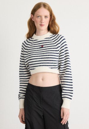 Gestreepte cropped trui in crème en marineblauw, met een ronde halslijn en geribbelde boorden. Kleine logo-detail op de voorkant.