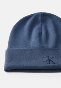 Marineblauwe gebreide beanie met omgeslagen rand en subtiel geborduurd "cK" logo aan de voorkant.
