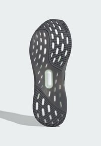 Sort athletic sko sål med tekstureret gummi, der har cirkulære og ovale udskæringer, og en forstærket mellemsål med brandingdetalje.