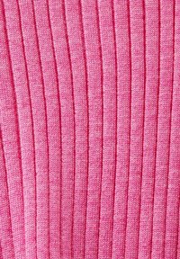 Lähikuva vaaleanpunaisesta purjekudotusta kangasta, kusit vertikaaliset tekstuuriviivat vaihtelevissa vaaleanpunaisen sävyissä.