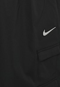 Černé šortky Nike vyrobené z hladké tkaniny, s boční kapsou a stříbrným logem. Přiléhavý střih s minimem švů.