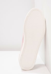 Baskets en mesh rose avec une semelle en caoutchouc blanc texturée, présentant un motif hexagonal et un logo discret près du talon.