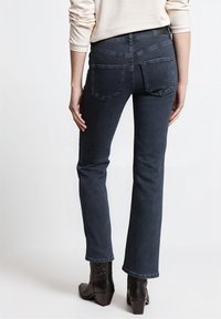 Tmavě modré džíny z denimu se střihm rovného střihu, vybavené dvěma zadními kapsami a středně vysokým pasem. Délka k lýtkům s čistým zakončením.