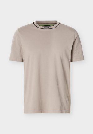 T-shirt beige à manches courtes et col rond côtelé, avec des rayures noires et vertes sur le col et le logo "BOSS" à l'intérieur du col.