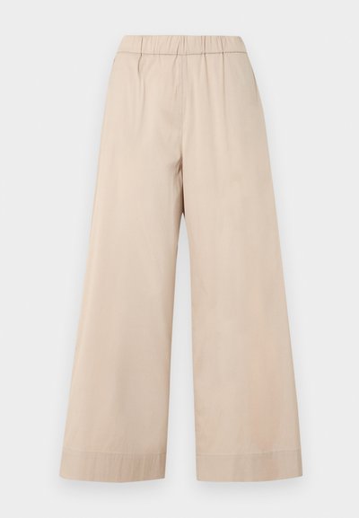 Μπεζ παντελόνια με φαρδιά μπατζάκια, ελαστική μέση και απλό τελείωμα, εμφανιζόμενα σε απλό φωτεινό φόντο.