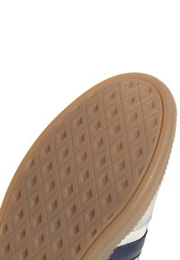 Rubber sneaker sole featuring a textured pattern of squares and diamonds in beige, with a navy and white upper edge.