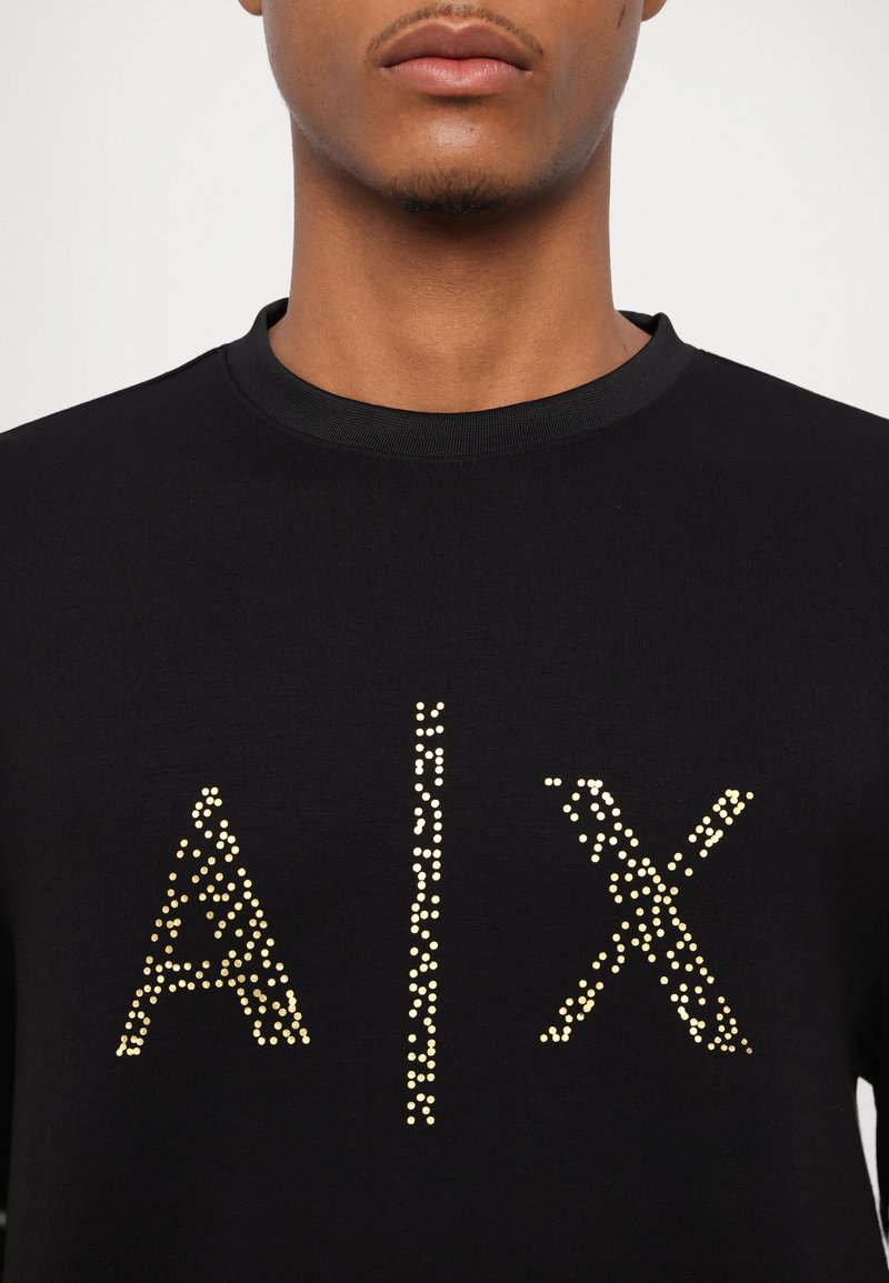 Schwarzer Sweatshirt mit einem goldpunktierten Design, das "AIX" auf der Vorderseite spellt, mit rundem Halsausschnitt und strukturiertem Stoff.