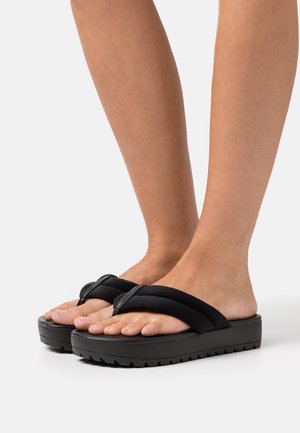 Sandali neri con piattaforma, dotati di cinturini morbidi e testurizzati, ampia zona per le dita dei piedi e una suola spessa e scanalata per una migliore aderenza. Design leggero per comfort e facilità d'uso.