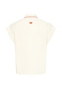 Chemise écrue à manches courtes avec col rouge cousu et petit cœur rouge centré en haut du dos.