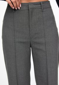 Grijze maatwerkbroek met een gladde textuur, uitgerust met een hoge taille, plooien en een rechte pijp. De stof heeft een subtiel patroon.