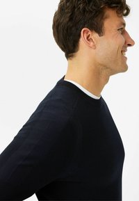 Navyfarbener Strickpullover mit Rundhalsausschnitt, gerippten Bündchen und strukturierten Schultereinsätzen. Glatte Stoffqualität mit taillierter Silhouette.
