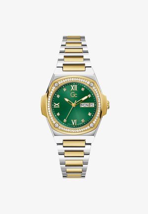 Zegarek z metalową kopertą złoto-srebrną o prostokątnym kształcie, zieloną tarczą, rzymskimi cyframi, diamentowymi akcentami oraz wskazaniami dnia i daty.