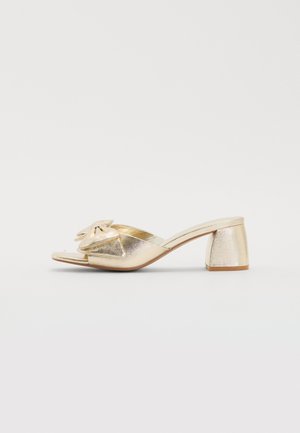 Gold metallic open-toe mules with a flat bow accent on the vamp, featuring a textured upper and a sturdy block heel.