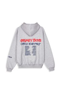 Sudadera gris con un bolsillo tipo canguro. Presenta texto en rojo y azul que dice "GRIMEY BOYS" y "CHECK YOUR FACT." Tejido suave, puños acanalados.
